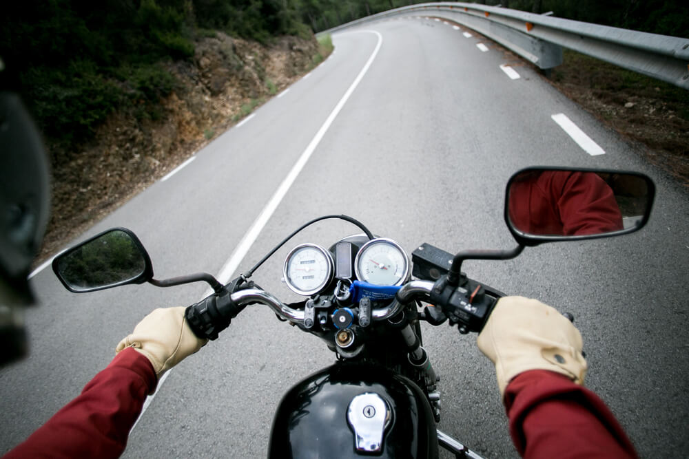 POV view of motorcycle driver driving through mountain road on high speed on vintage retro motorcycle