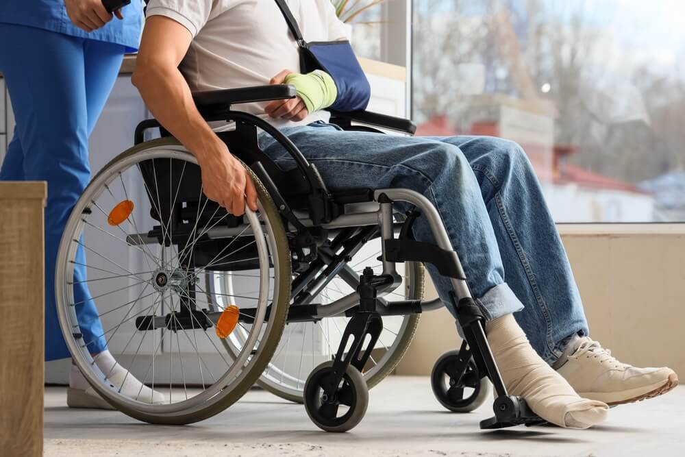 Injured young man in wheelchair with doctor at home, representing recovering damages in a Vancouver injury claim