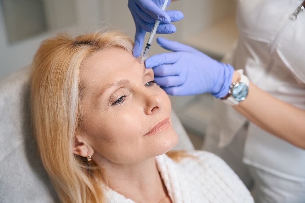 Woman receiving Botox injection in forehead by medical professional – learn your rights if injectable treatments cause complications.