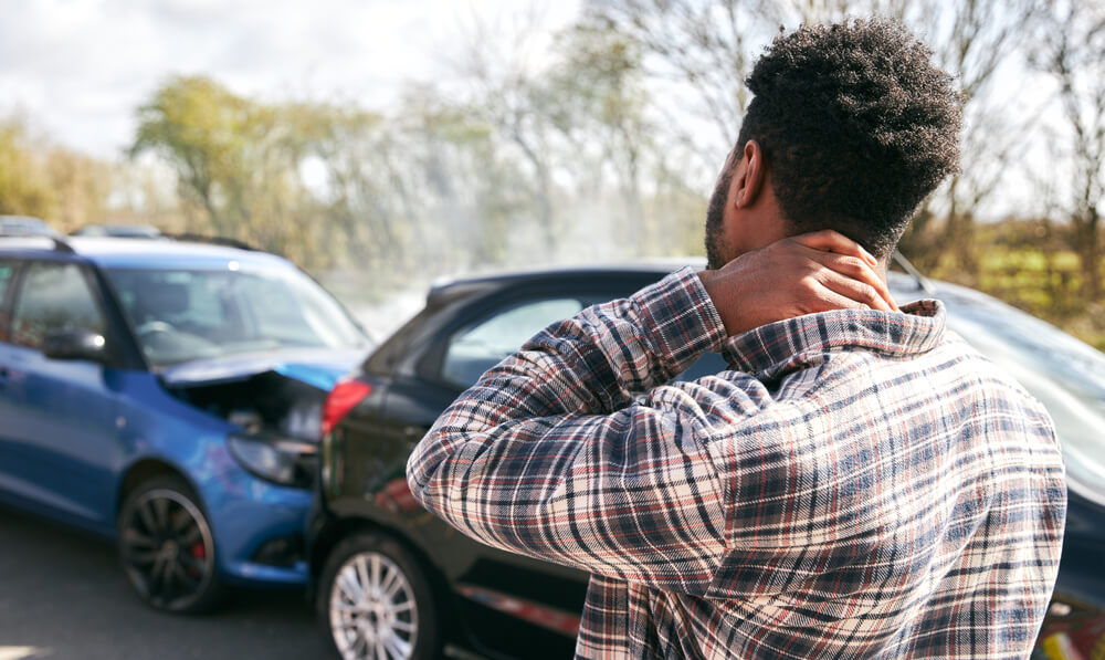Man holding neck after rear-end collision, showing symptoms of whiplash after a car accident