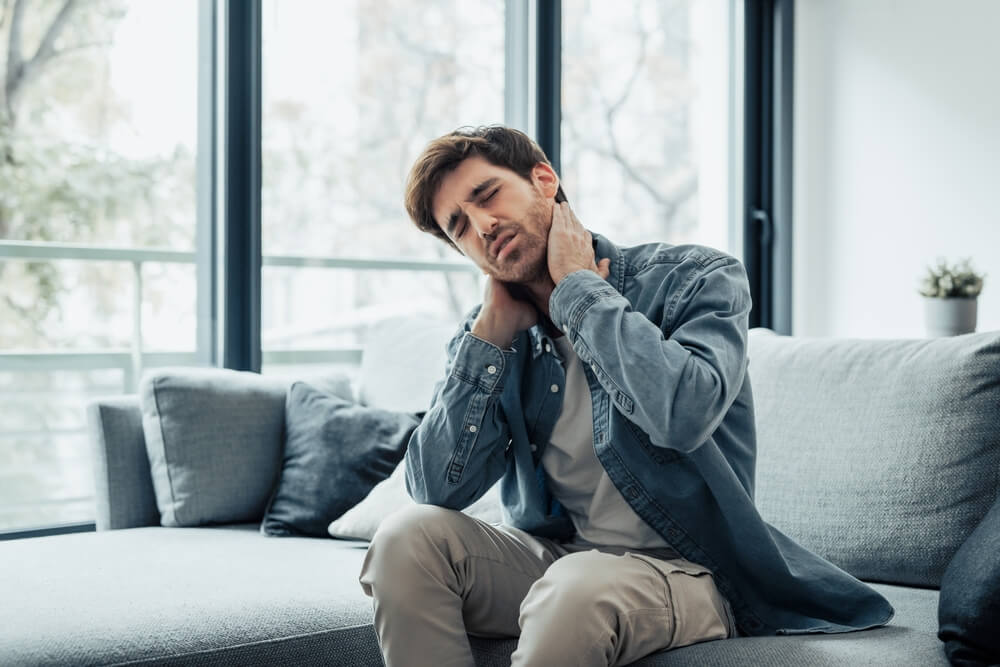 Man suffering from chronic neck pain at home after an accident — consult a Vancouver chronic pain lawyer for legal help.