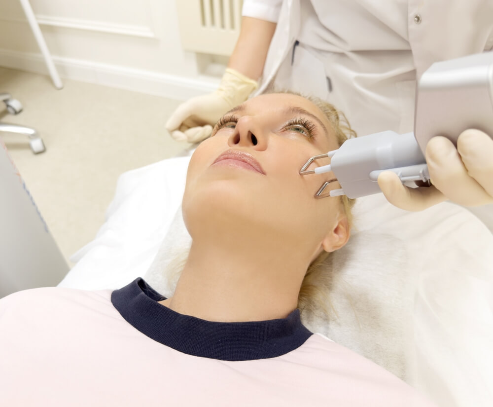 Woman receiving cosmetic laser skin treatment at a clinic — potential risks of burns, blisters, and pigmentation injuries from laser procedures.