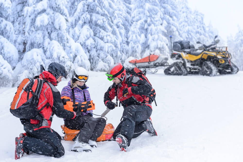 Ski patrol rescuing an injured skier after a winter sports accident in BC.