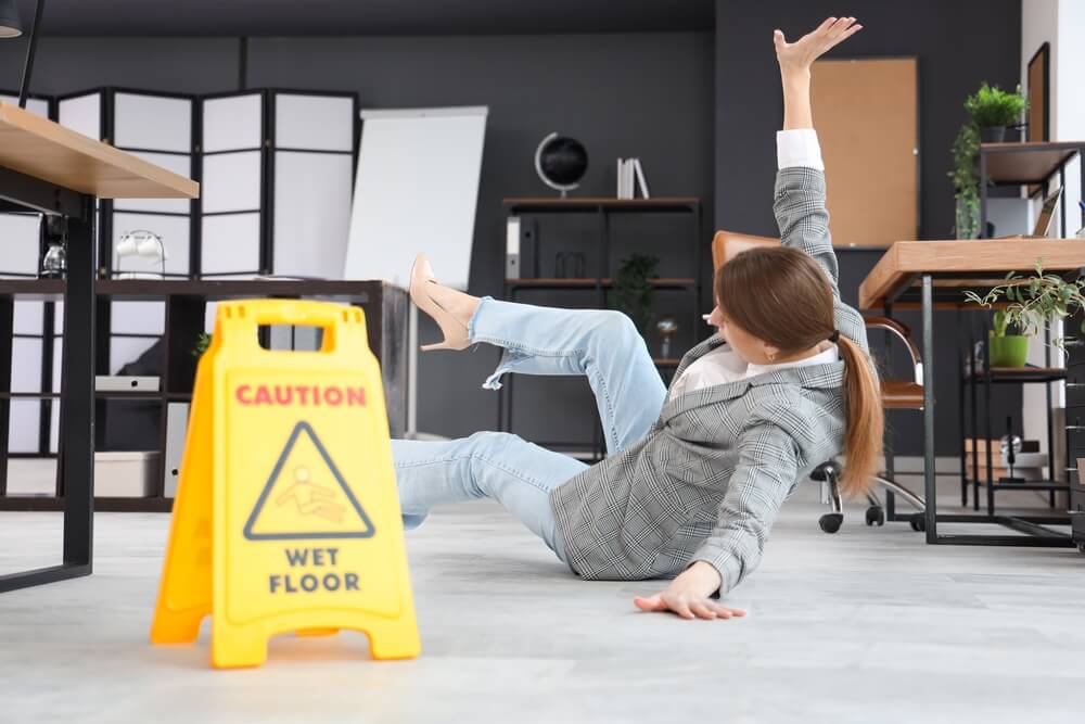 Woman slipping on a wet floor near a caution sign in a Vancouver office
