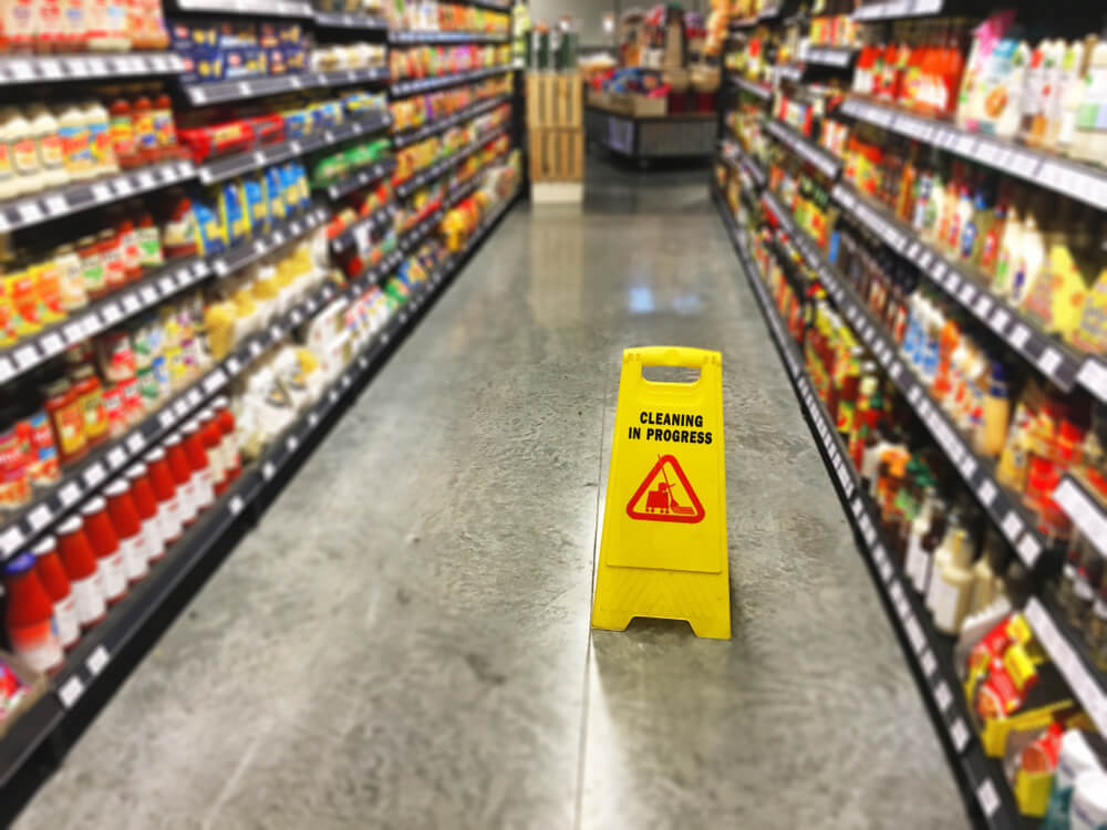 Vancouver grocery store slip and fall hazard with a yellow cleaning warning sign in a supermarket aisle